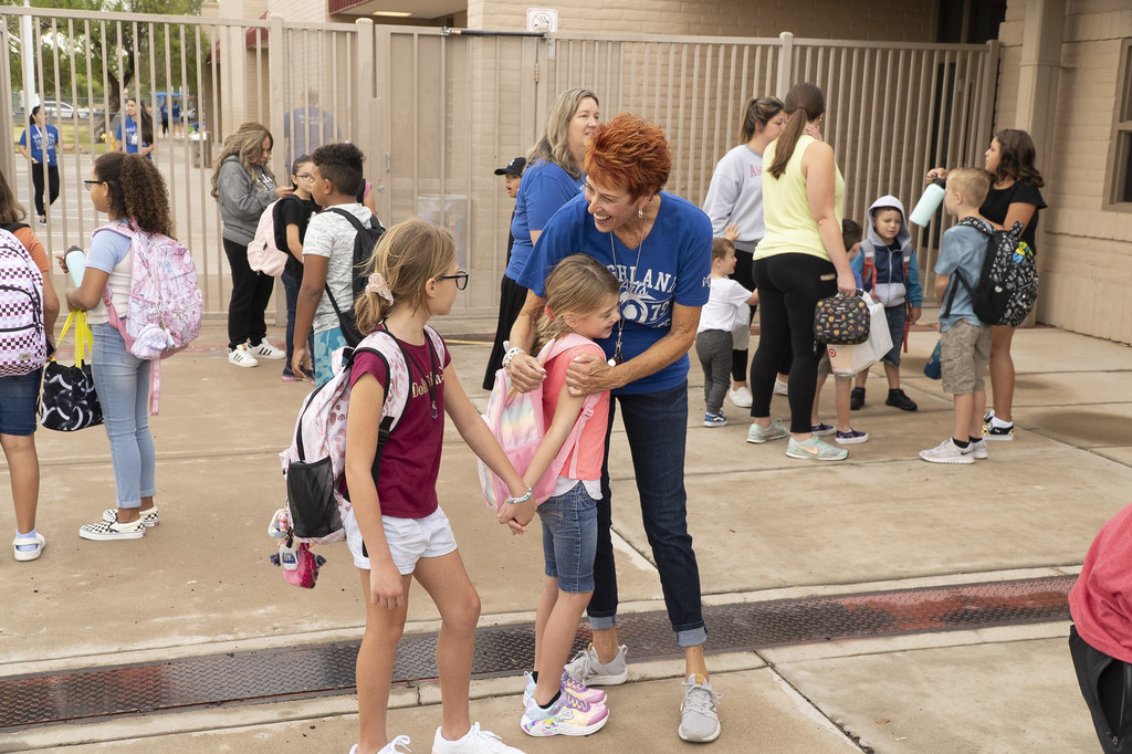 Elementary school teacher hugging and welcoming female students