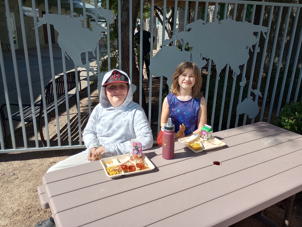 a boy and a girl sitting at a picnic table