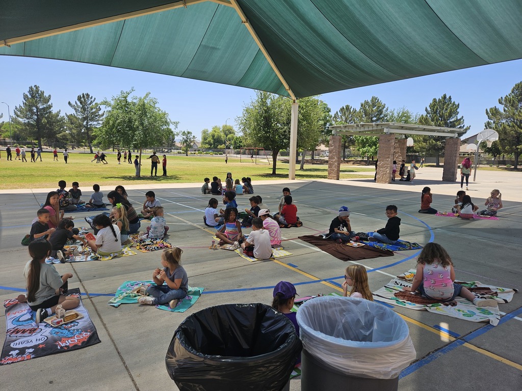 many children sitting on plcnic blankets eating lunch