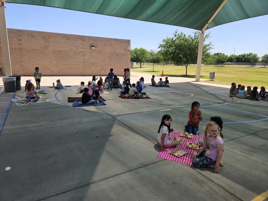 girls sitting on a picnic blanket eating lunch