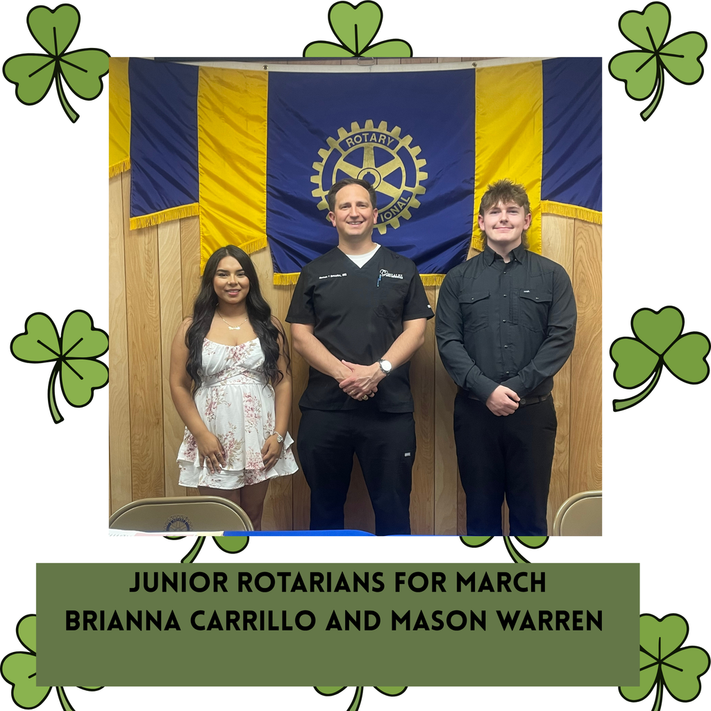 two students posing with Nathan Gonzalez in front of the Rotarian flag