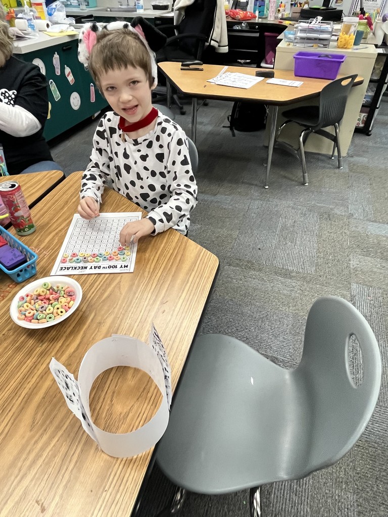 Child in polka-dot pajamas, seated at a table with a worksheet, and a plate of snacks.