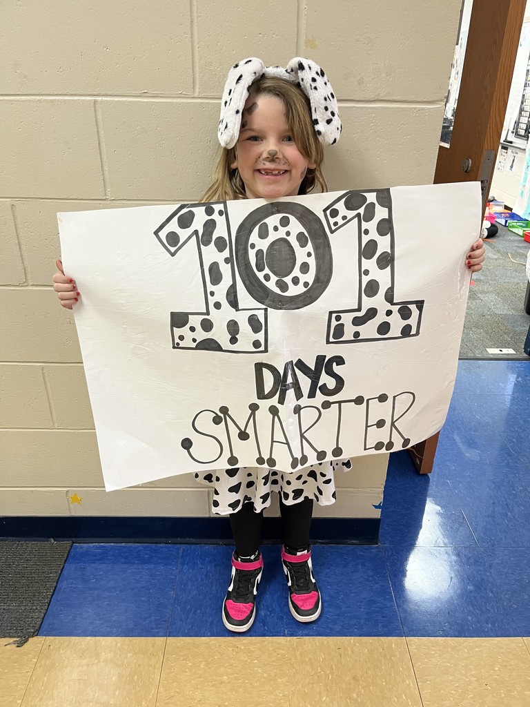 Child holding a sign that says "101 Days Smarter" with a Dalmatian hat on.