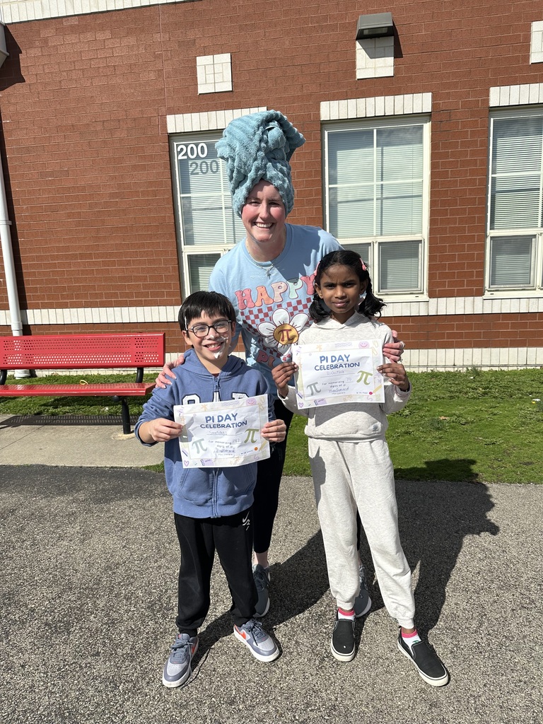 Three children, two holding certificates, stand in front of a brick building with a bench and windows.