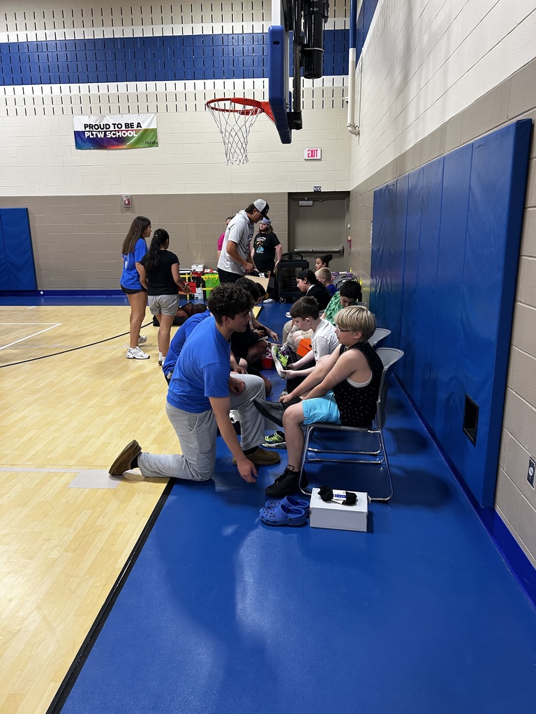 Students help younger students try on new shoes.