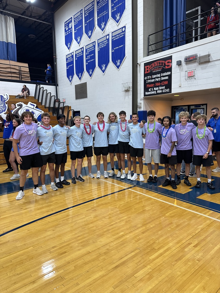 Group of young athletes wearing purple shirts and black shorts on a basketball court. They are standing together with medals around their necks.