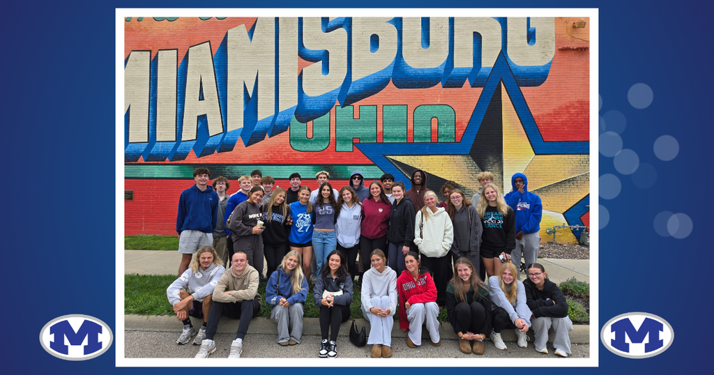 Group of people in casual clothes posing for a photo in front of a Miamisburg, Ohio mural.