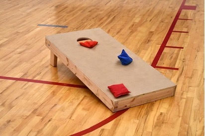 Cornhole Goal with red and blue cornhole bags on a gym floor.