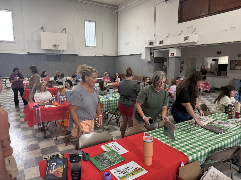 Staff socializing at red and green tables about yearbooks