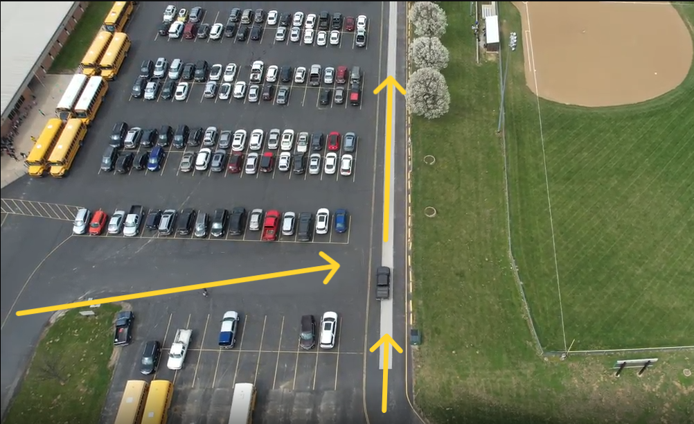 A parking lot with yellow arrows showing cars where to enter and what lane to follow.