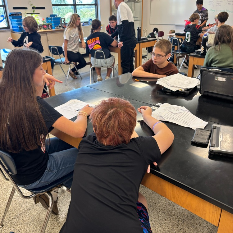 students sitting at a lab table in a science classroom
