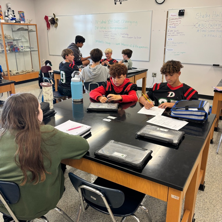 students sitting at a lab table in a science classroom