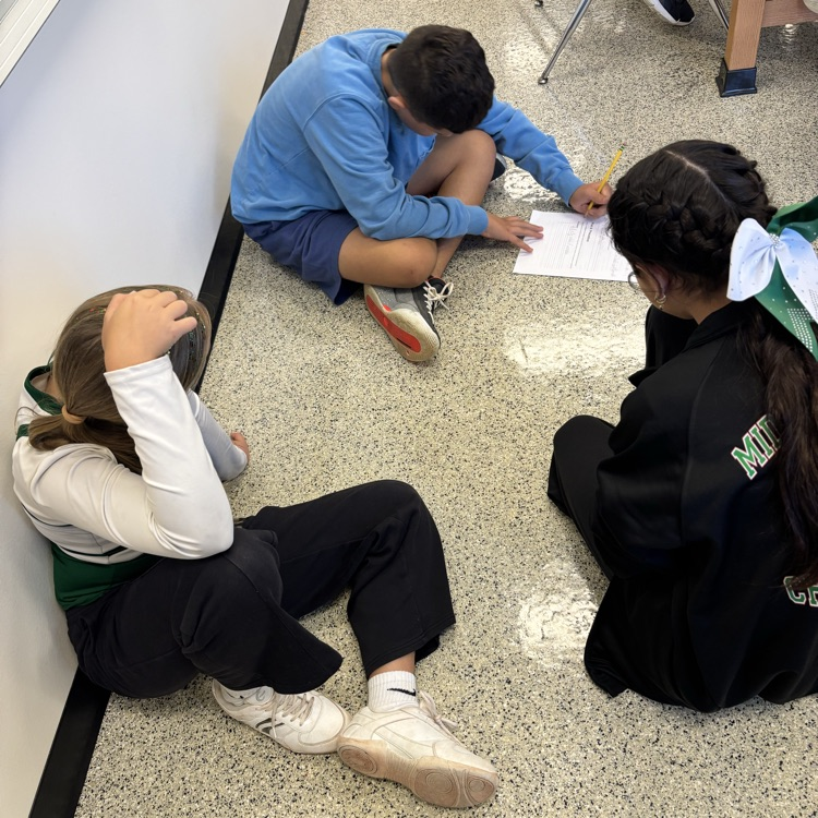 students sitting on the floor completing a science lab