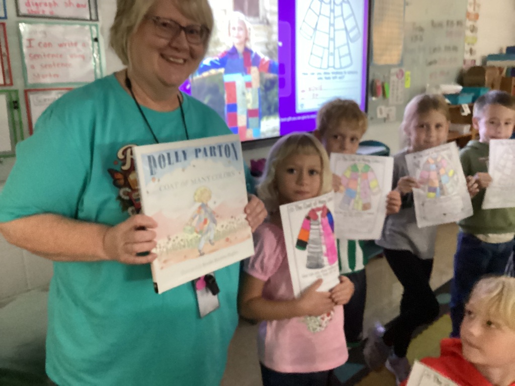 Teacher holding the book Coat of Many Colors by Dolly Parton