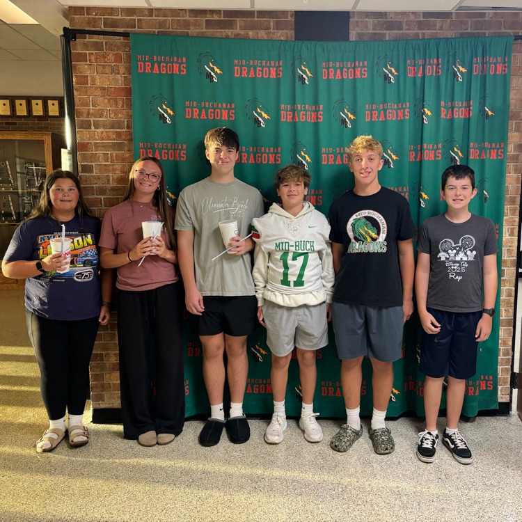 students standing in front of a green background with dragon on it