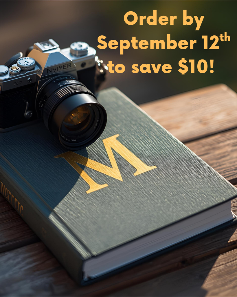 a book with the letter M on the cover with a camera sitting on top.