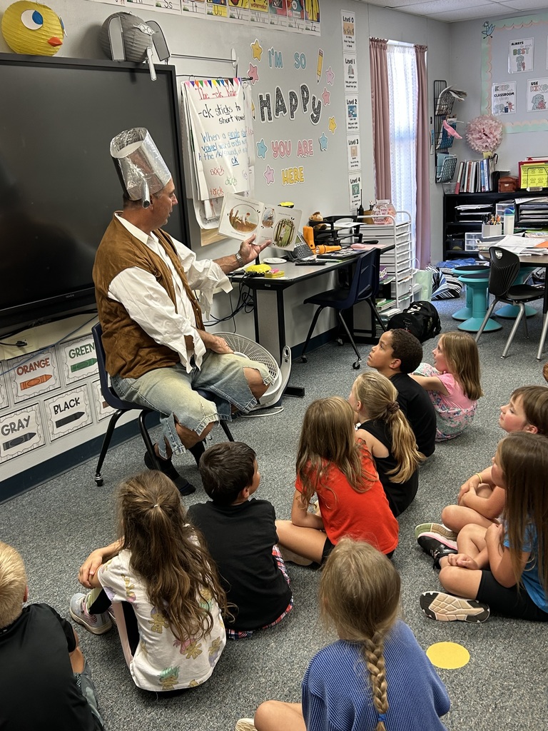 Pictures of Mr. Becker reading to 1st grade as Johnny Appleseed.