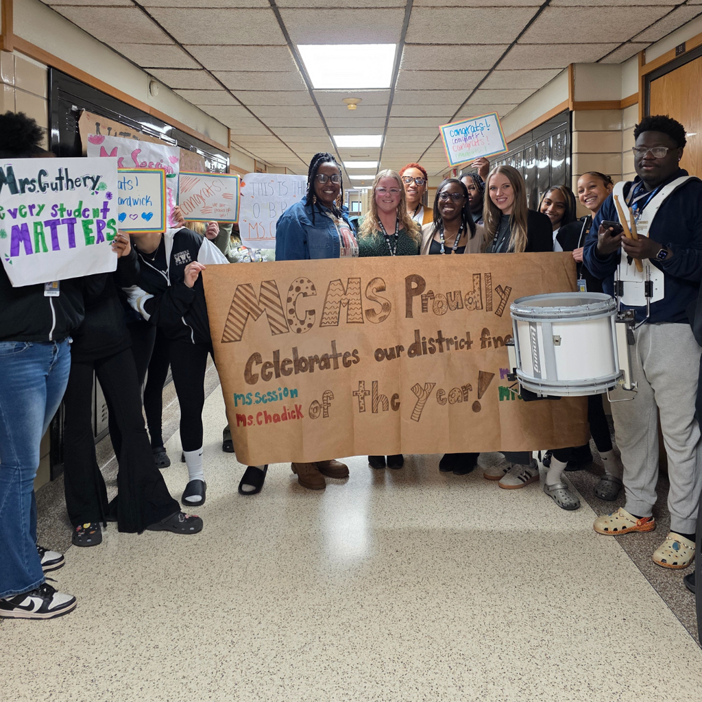 students holding signs for each of the finialists and the aduts stading behind a large sign
