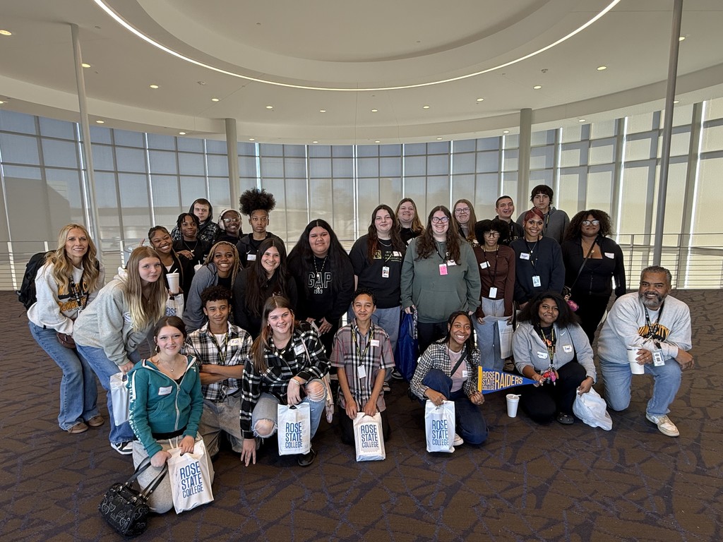 Students from Mid-Del attended Rose State College today. They are smiling in a group photo for the camera. They are holding Rose State College bags.
