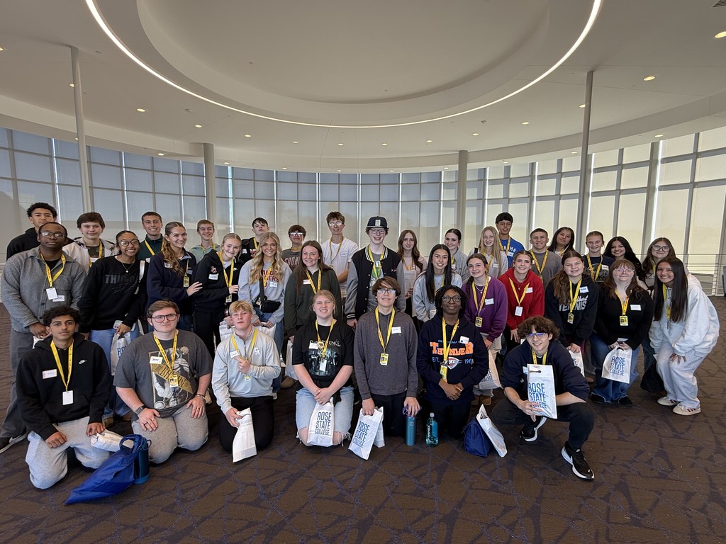 Students from Mid-Del attended Rose State College today. They are smiling in a group photo for the camera. They are holding Rose State College bags.