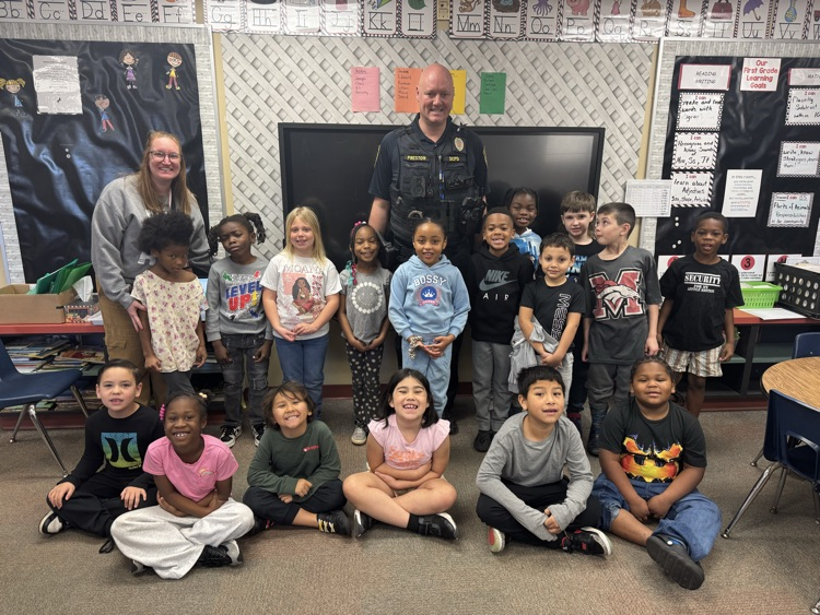 Students from Mrs. Shae’s class sitting in rows for a picture with a DCPD officer.
