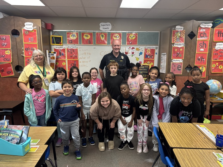 Students from Mrs. Dagg’s class sitting in rows for a picture with a DCPD officer.