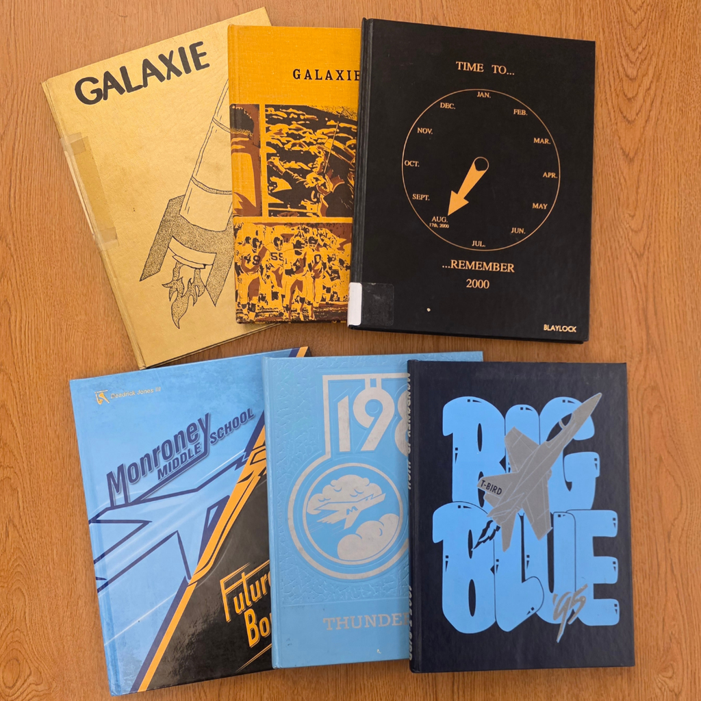 3 black and gold yearbooks with 3 blue and black yearbooks 