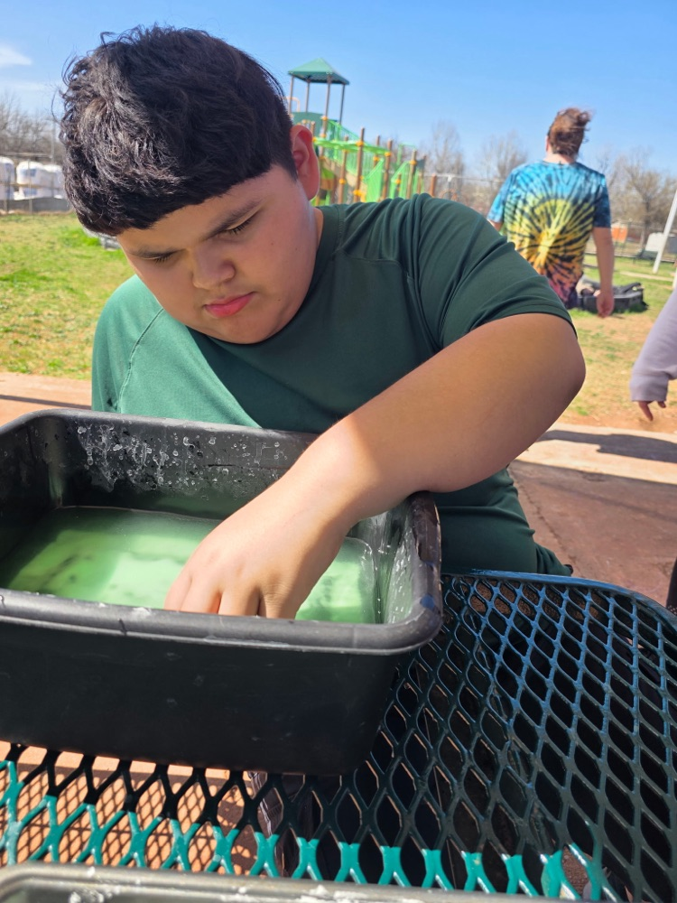  hands-on sensory activity for special education students. Children sticking their hands in a bucket of green slime for St. Patrick’s Day. 