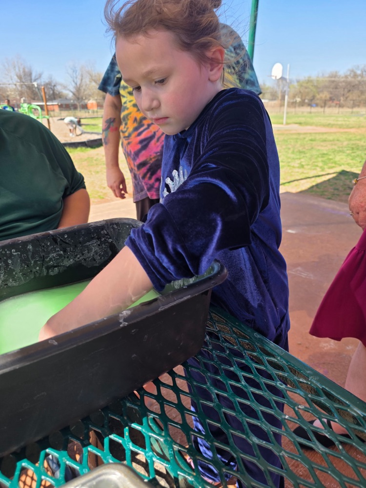  hands-on sensory activity for special education students. Children sticking their hands in a bucket of green slime for St. Patrick’s Day. 