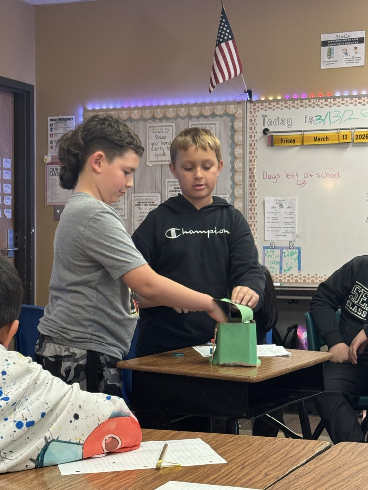 leprechaun traps made by fourth graders. The students are in front of the room, presenting them.