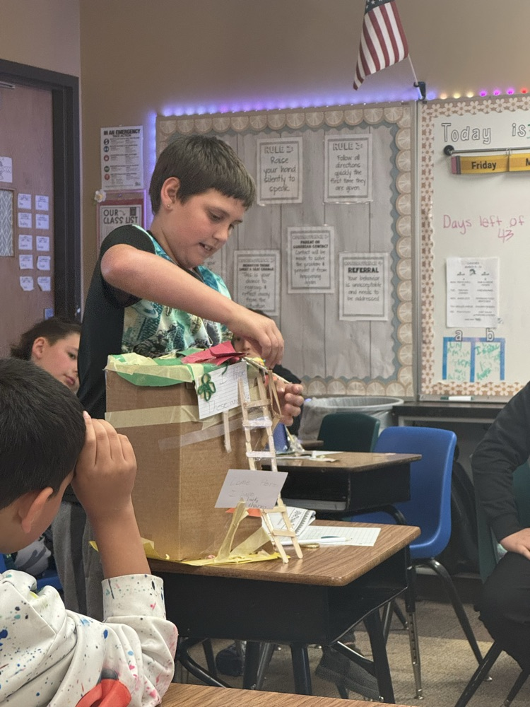 leprechaun traps made by fourth graders. The students are in front of the room, presenting them.
