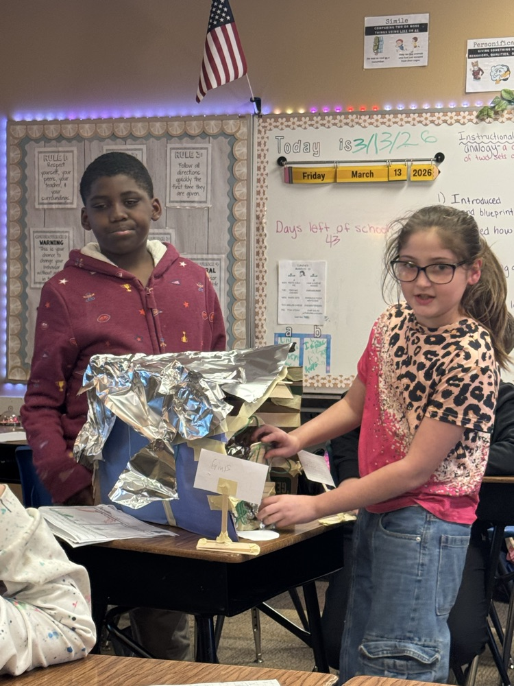 leprechaun traps made by fourth graders. The students are in front of the room, presenting them.