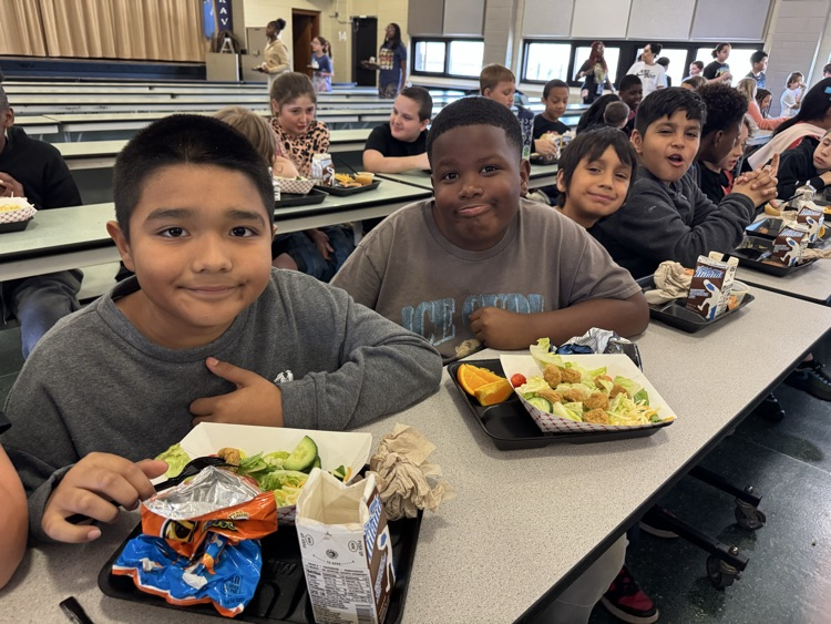 Photos of students in the cafeteria. Enjoying lunch, going through the line to grab a tray, and chatting with friends.