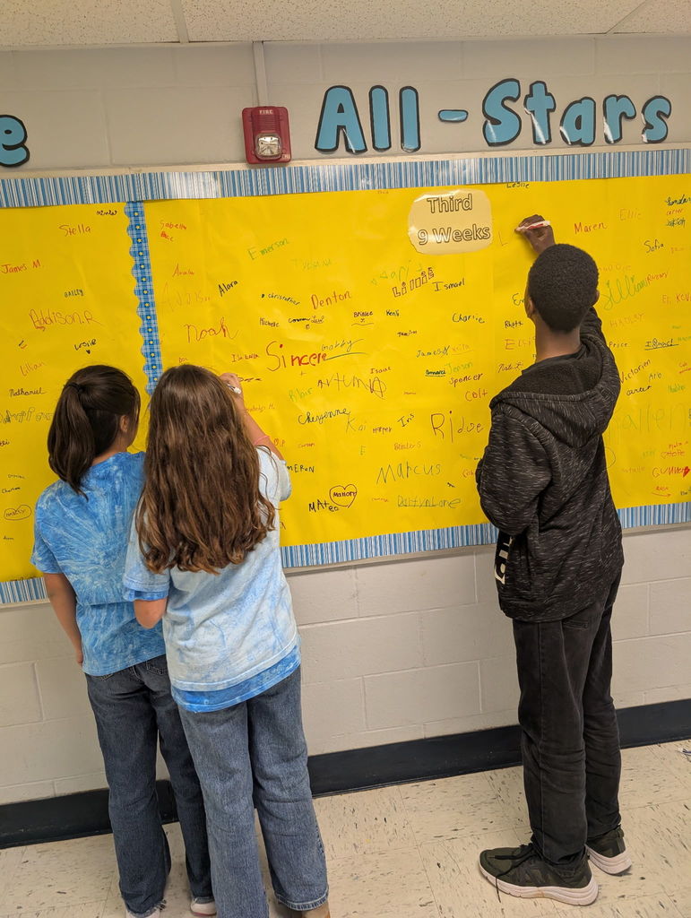 Barnes elementary students sign the Attendance All Stars Board in the hallway.