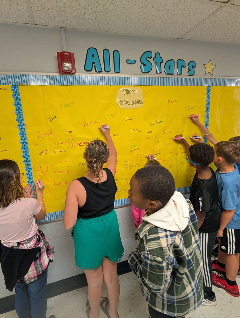 Barnes elementary students sign the Attendance All Stars Board in the hallway.