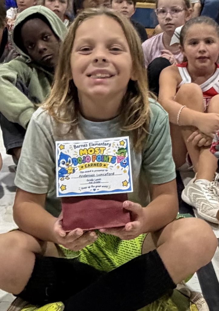 A student holds a certificate for most dodo points in front of a group of students.