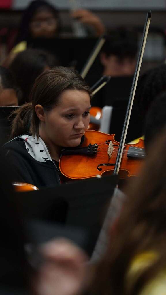 A student in a black shirt is playing the violin