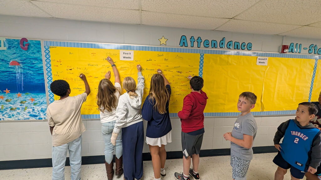 Students are shown signing the Attendance All Star Board for the 1st 9 weeks of school.