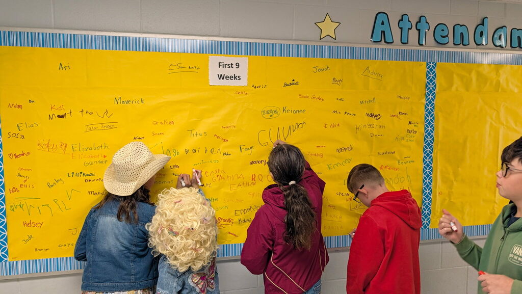 Students are shown signing the Attendance All Star Board for the 1st 9 weeks of school.