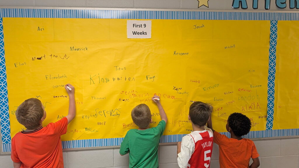 Students are shown signing the Attendance All Star Board for the 1st 9 weeks of school.