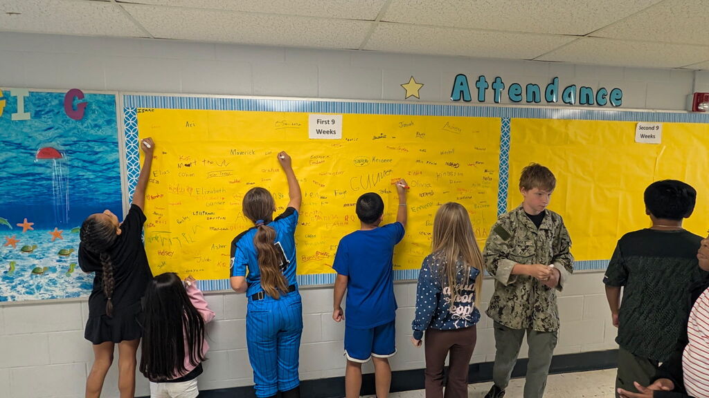Students are shown signing the Attendance All Star Board for the 1st 9 weeks of school.