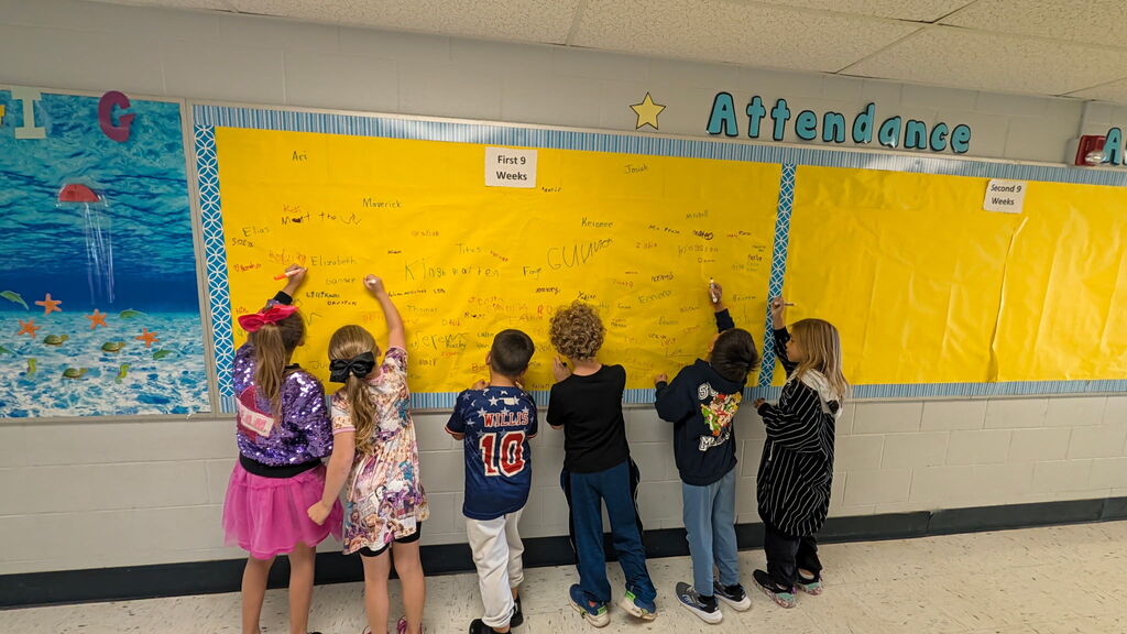 Students are shown signing the Attendance All Star Board for the 1st 9 weeks of school.