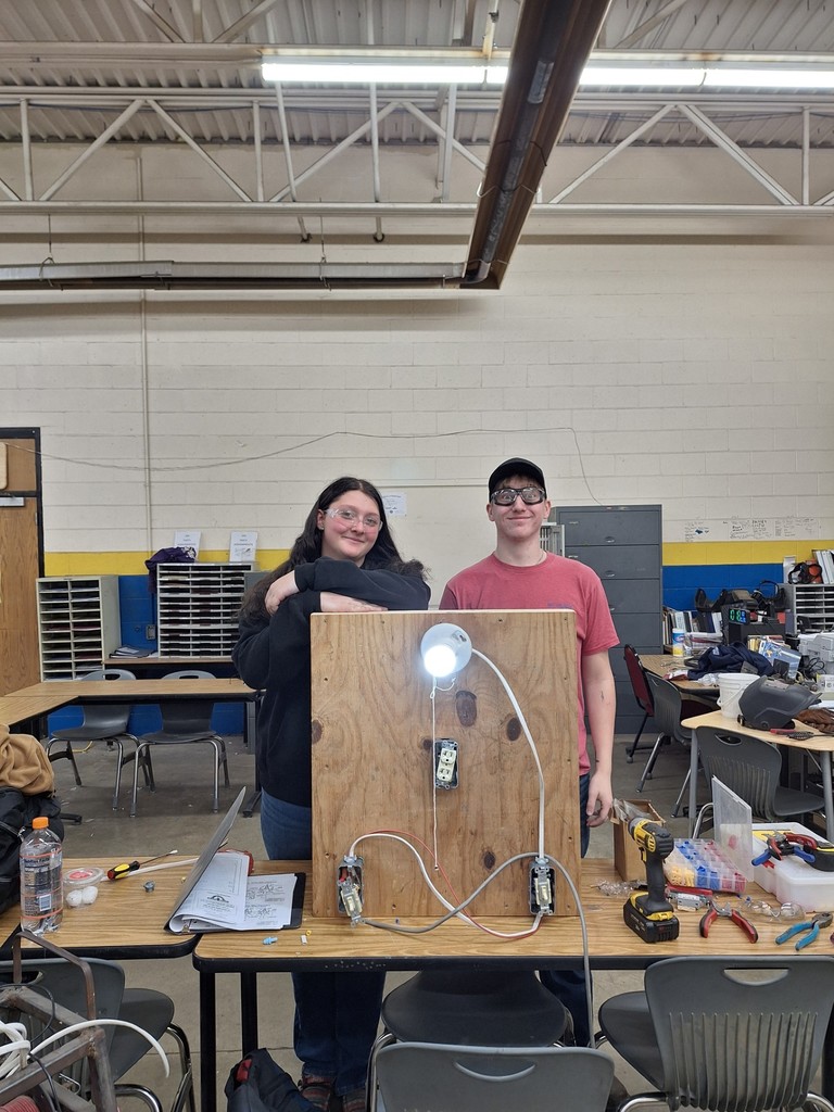 two students pose with their successfully wired 3 way switch