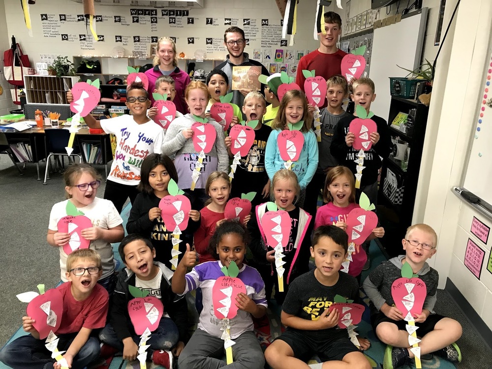 Mrs. Bell's class poses with apple life cycle craft