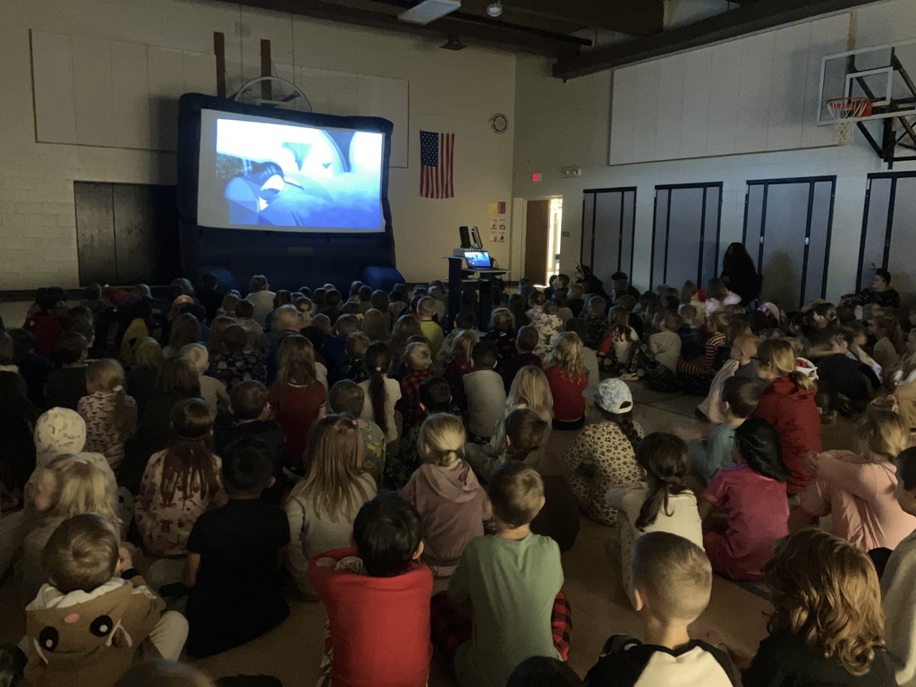 Students watching Wild Kratts in the gym on large inflatable screen