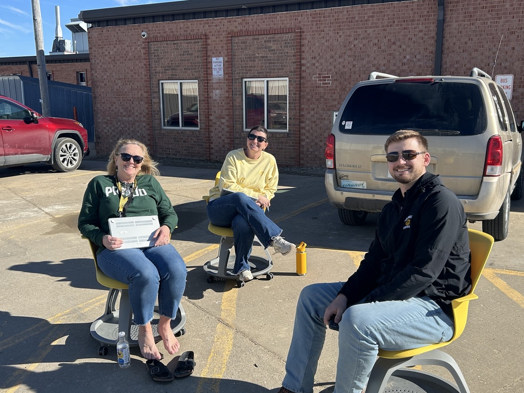 MPHS math teachers sitting outside in yellow rolling chairs with computers having a conversation