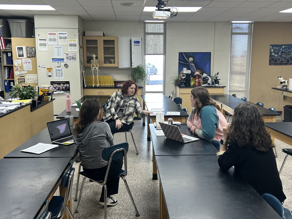 MPHS Science teachers sitting at tables with laptops open having a conversation