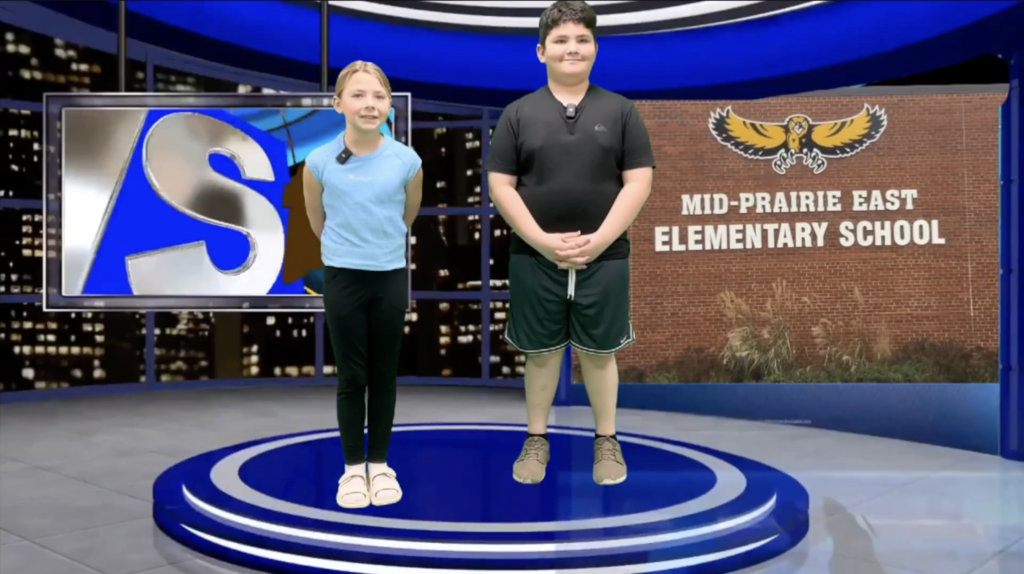 Two students standing in a news studio background with Mid-Prairie East Elementary shown in the background also