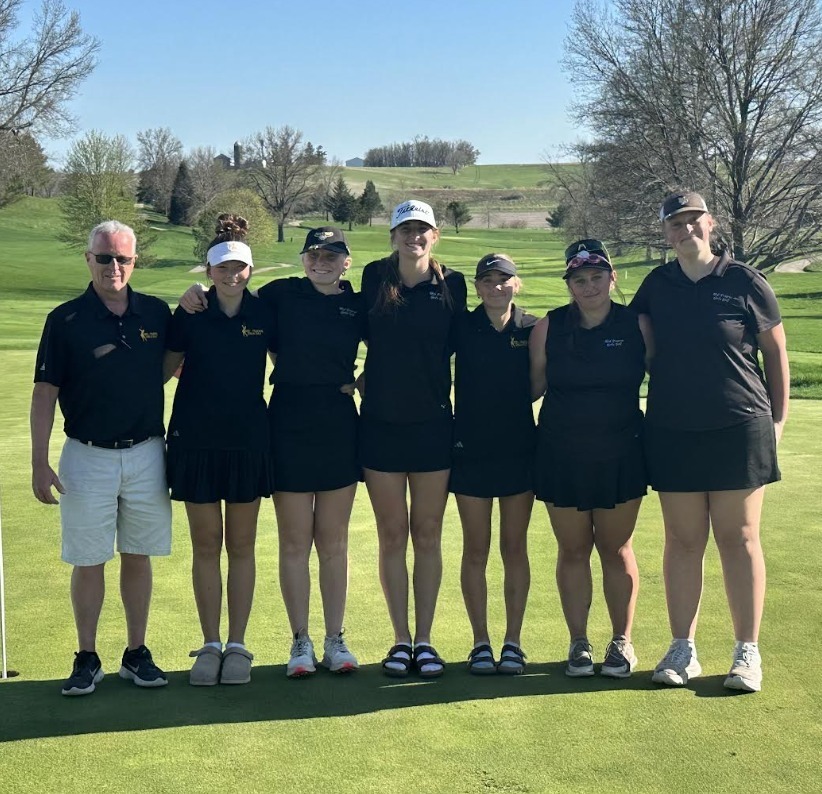 Girls golf team posing with coach out on the course