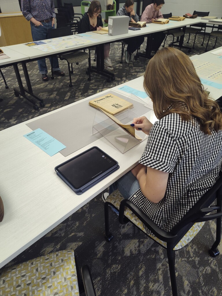 Students sitting at a table looking through books, papers and maps together